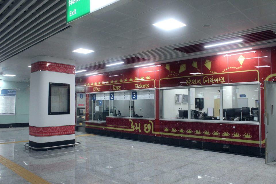 Metro station concourse with glazed ticket counters and metal ceiling